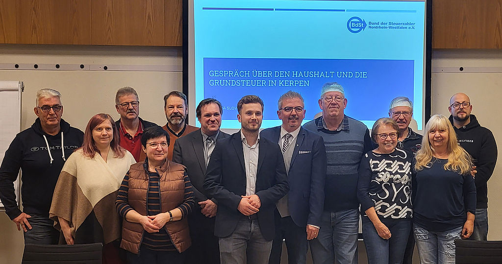 Gruppenfoto von zwölf Mitgliedern des Bürgerbündnisses Kerpen, die sich am Abend mal zur Rechten und zur Linken um BdSt-Referenten Joscha Slowik versammelt haben. Vier der Zwölf sind Frauen.