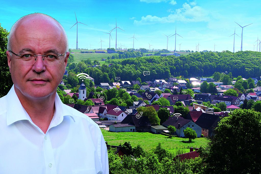 Porträt eines Mannes vor ländlicher Kulisse mit Windrädern und digitalen Symbolen über Häusern, die Digitalisierung im Dorf symbolisieren