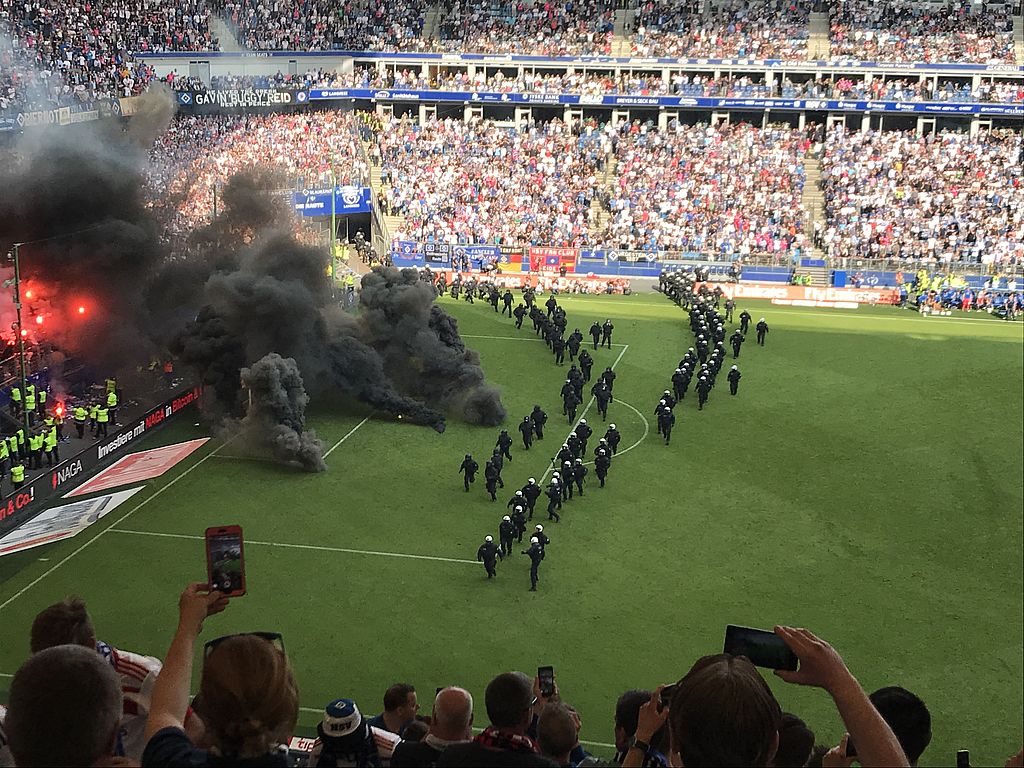 Fans zünden auf dem Spielfeld im Volksparkstadion schwarze Pyrotechnik. Dies wird von einem großen Polizeiaufgebot begleitet.